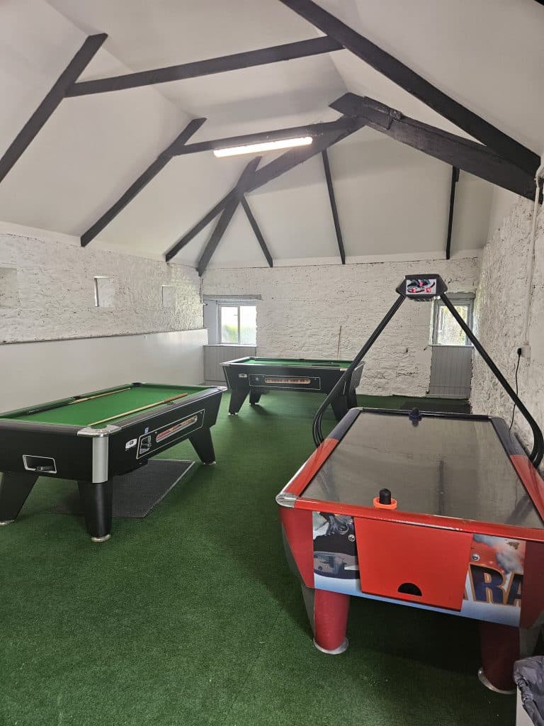 A recreational room featuring a pool table, air hockey table, and a dart board on the wall.