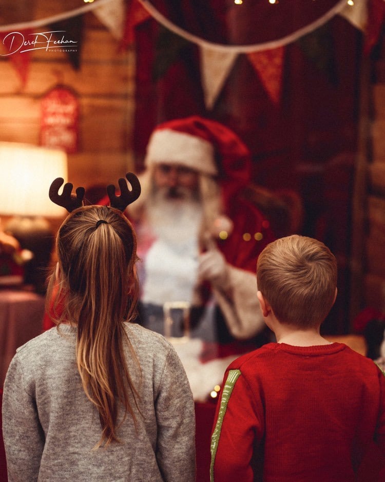 Christmas scene featuring Santa Clause greeting two children.