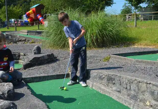 Two boys playing mini golf at Nore Valley Park.