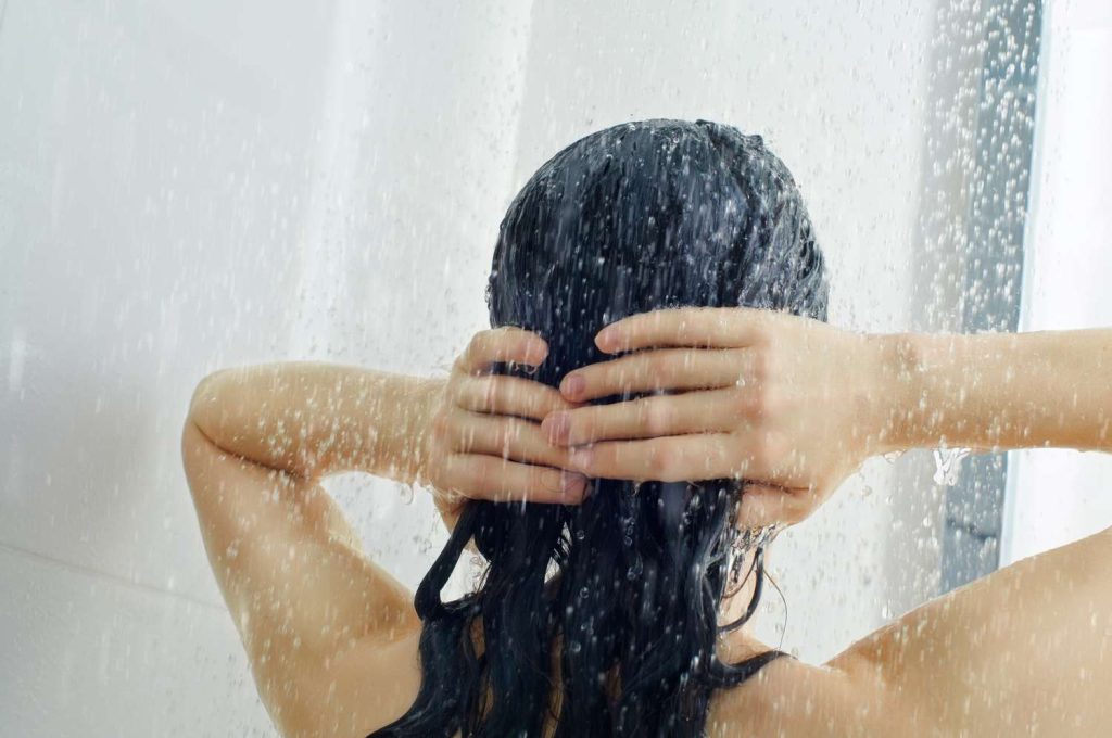 Woman washing her dark hair in a shower.
