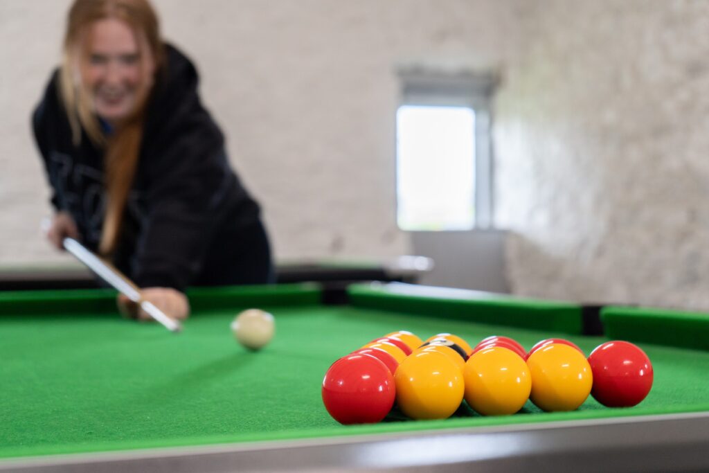 a girl playing pool in the games room